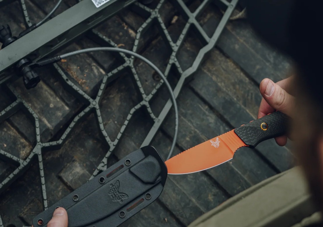 A fixed blade being drawn from a moulded sheath, showing the bolted handle scales that make a rehandle possible